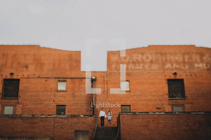 couple standing in front of a brick warehouse building 