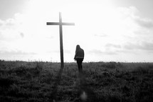 a woman praying in front of a cross