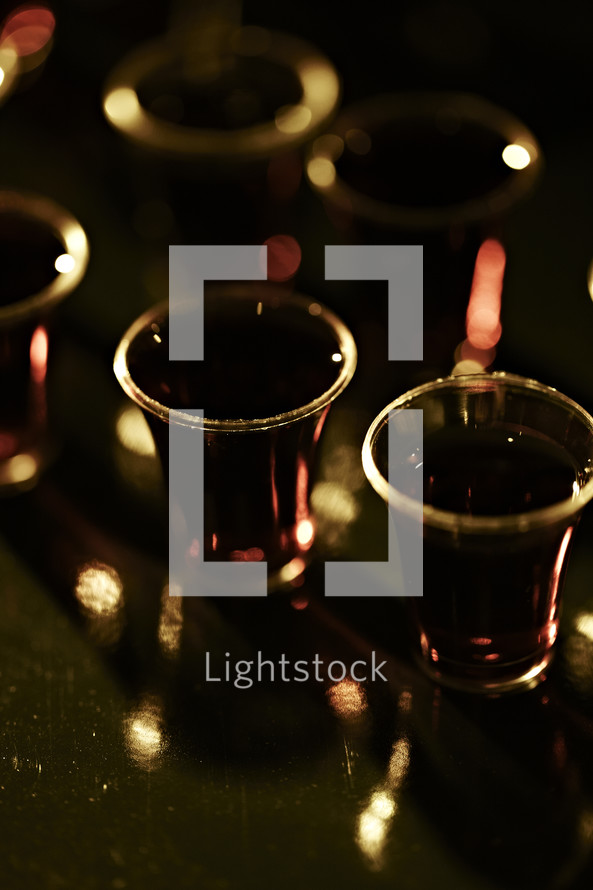 Communion cups with red wine on a translucent background.