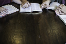 girl holding hands in prayer around a table 