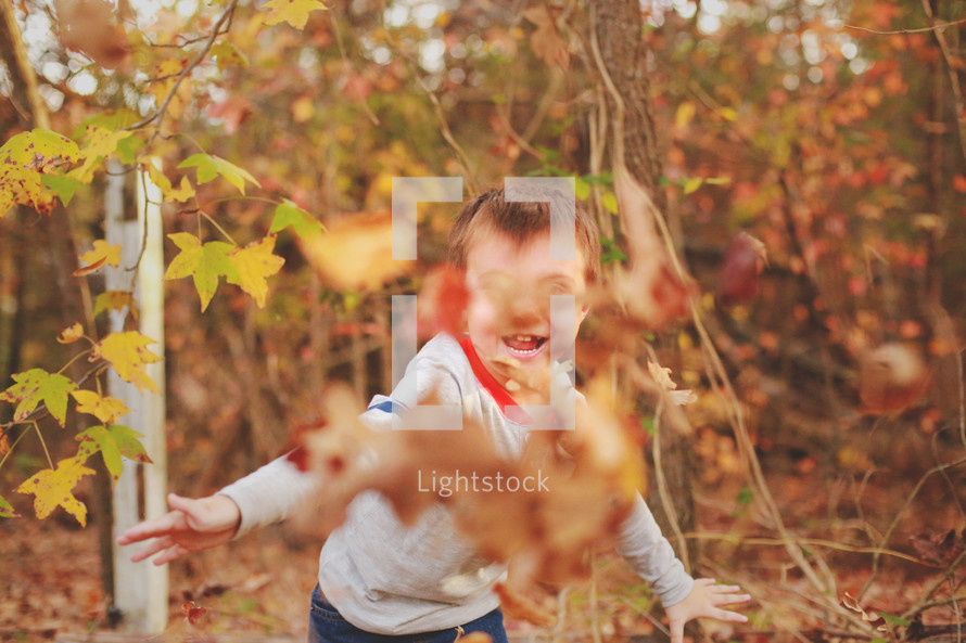 a boy playing in fall leaves 