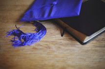 a graduation cap lays on top of a Bible