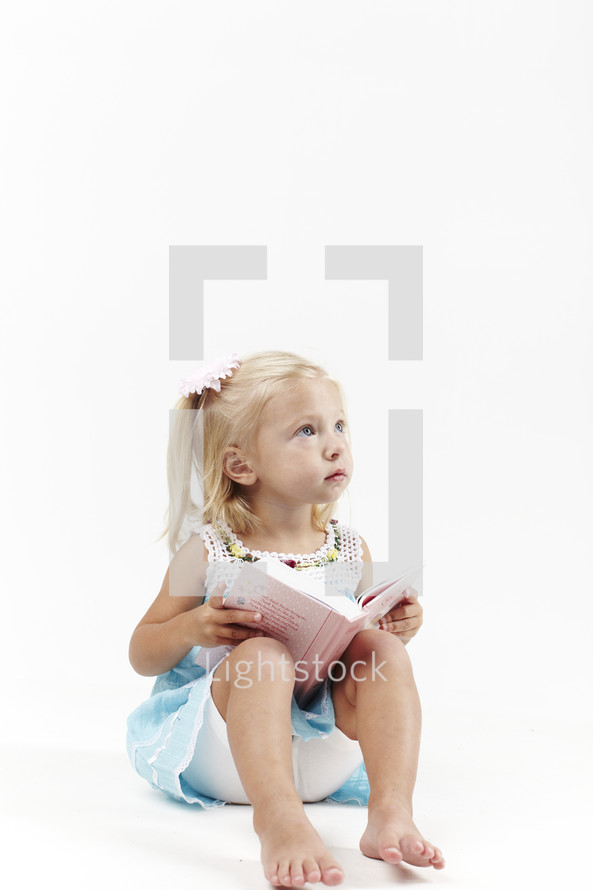A little girl reads her first children's Bible.