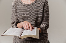 woman sitting on a stool reading a Bible 