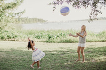 A little girl throwing a beach ball to a young woman.