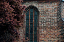 A tall arched window in a brick church.