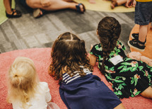 children sitting on the floor around a teach 