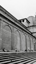 people sitting on steps in front of the Vatican wall in Rome 