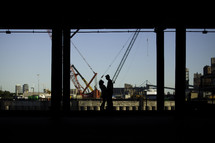 silhouette of a couple standing under an overpass 