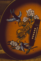 "Hope, freedom, faith, love" emblem on an acoustical guitar.