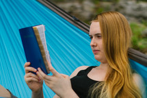 woman reading a Bible on a hammock