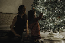 a mother and daughter decorating a Christmas tree 