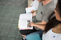 young college students with book sitting and reading together.