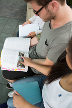 college students on campus sitting reading a book 