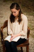 a young woman sitting and praying over an open Bible 