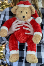 A child holding a Santa Claus teddy bear toy at Christmas 