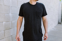 Torso view of a man wearing a blank black tshirt with a chest pocket.