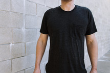 Torso view of a man wearing a blank black tshirt with a chest pocket.