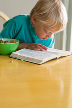 morning devotional, boy child reading his Bible and eating milk and cereal 