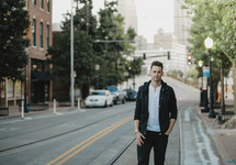 portrait of a man standing on the side of a downtown street 