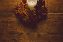 Candle with wreath of fall leaves on a wooden table -- Thanklessness decor.