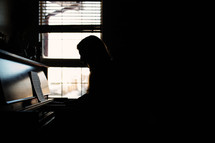 a silhouette of girl playing the piano
