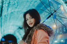 a woman holding an umbrella standing in front of Christmas lights 