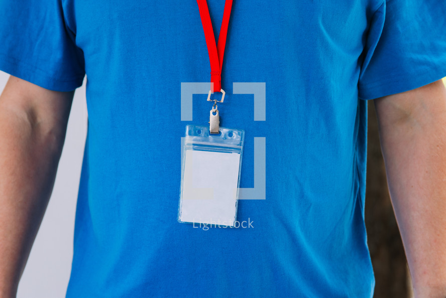 Torso of a man in a blank blue tshirt wearing a lanyard.