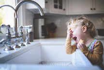 toddler crying by a sink 