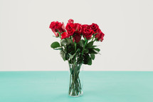 Red roses in a clear glass vase.