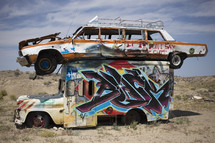 abandoned cars covered with graffiti in a desert 