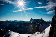 sunburst over jagged snow covered mountains 