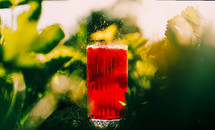Ice cube falls in refreshing summer strawberry lemonade drink. Splashes. Red cold fizzy beverage cocktail. Mojito with lime and strawberry. High quality