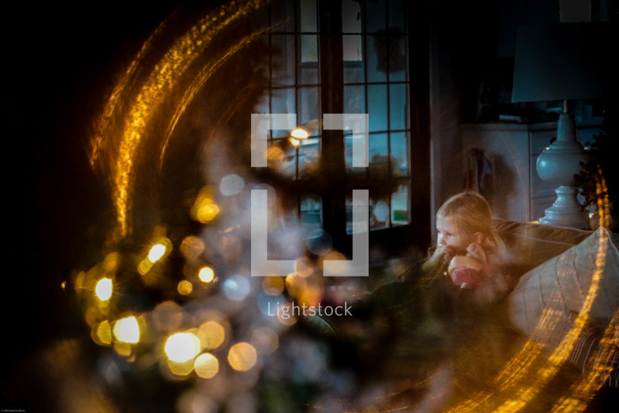 view of a little girl on a couch through a mirror at Christmas time 