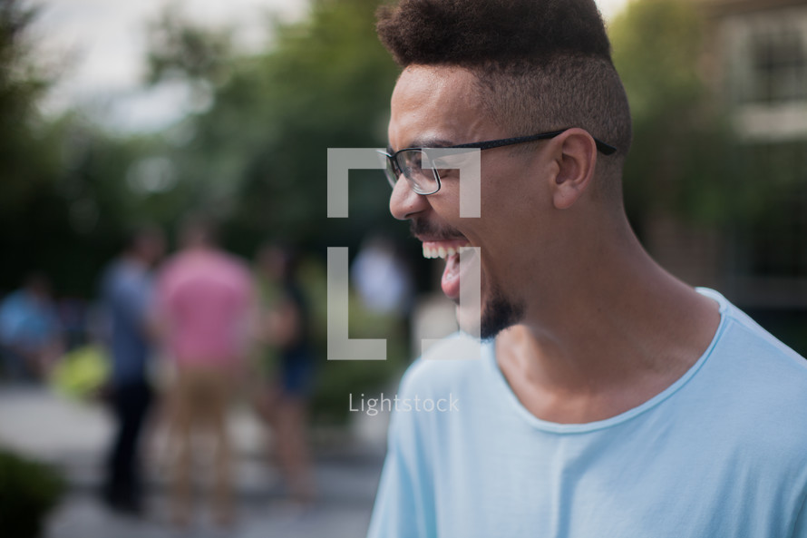 headshot of a young man laughing at an outdoors summer party 
