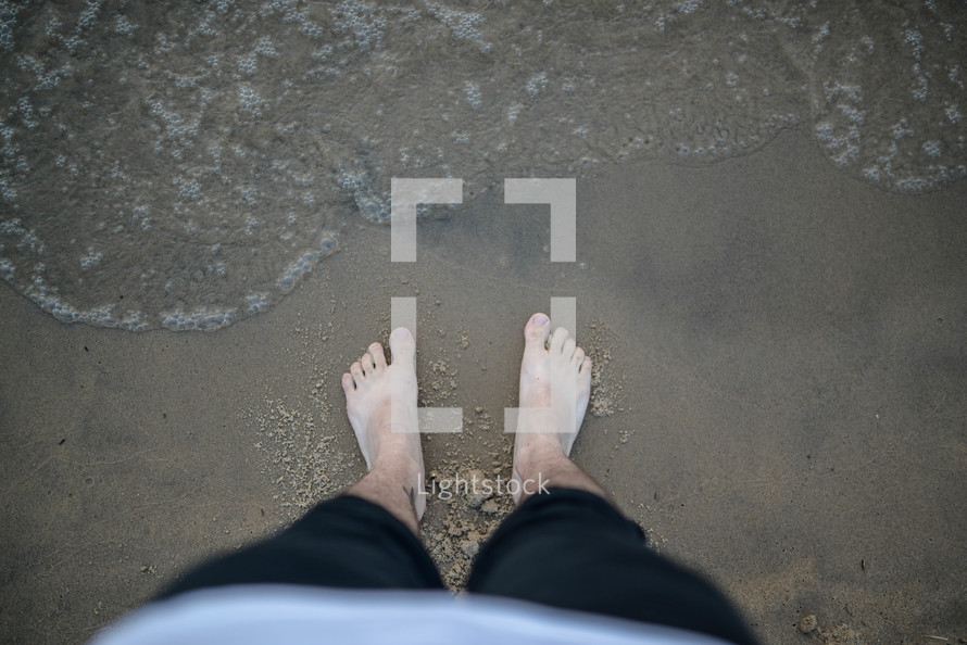 man with bare feet in the sand on a beach 
