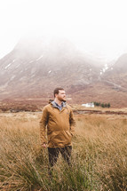 man standing in tall grass in a field in a Scottish Valley