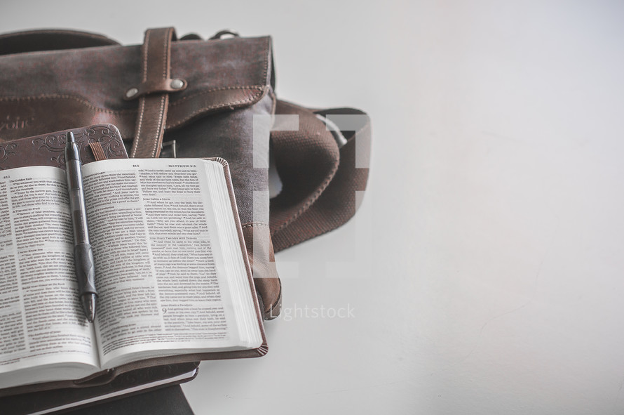 messenger bag, open Bible, and journal 
