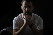 a man in prayer in a dark room 
