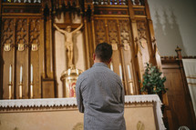 Young man praying in front of tabernacle in Catholic church