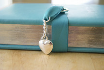 spine of a teal Bible and heart locket 
