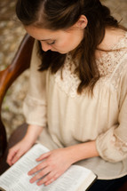 a young woman sitting and reading a Bible 