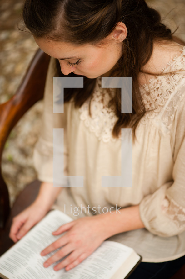 a young woman sitting and reading a Bible 