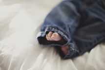 infant feet poking out of denim jeans