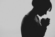 Silhouetted woman praying