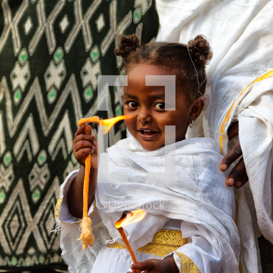 little girl holding flames at a celebration in Ethiopia 