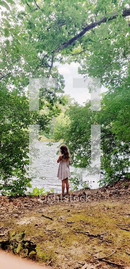 girl standing on a lake shore in summer 