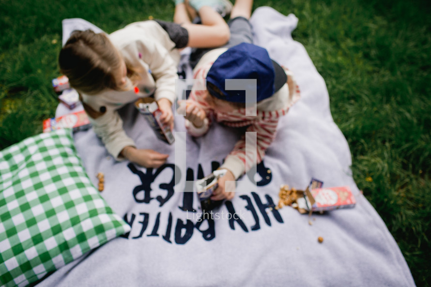 kids eating cracker jacks on a blanket in the grass