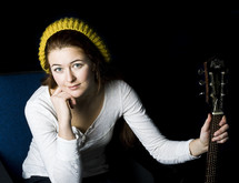 woman in a knit hat holding a guitar neck