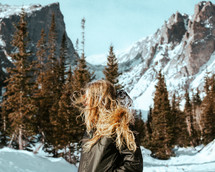 woman standing in a valley near snow covered mountains